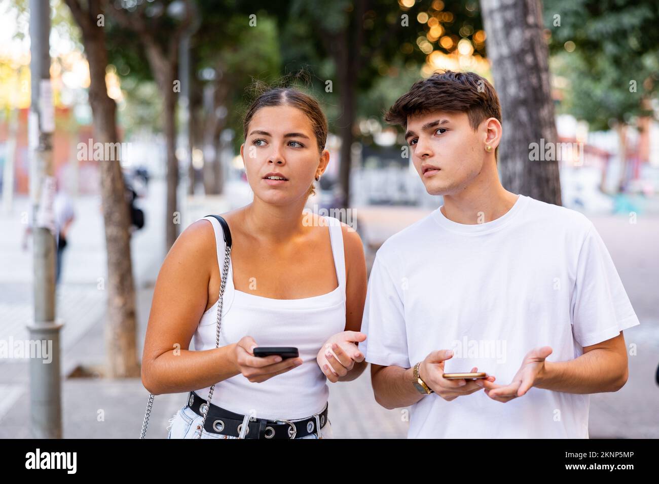 Young couple using smartphones while walking Stock Photo