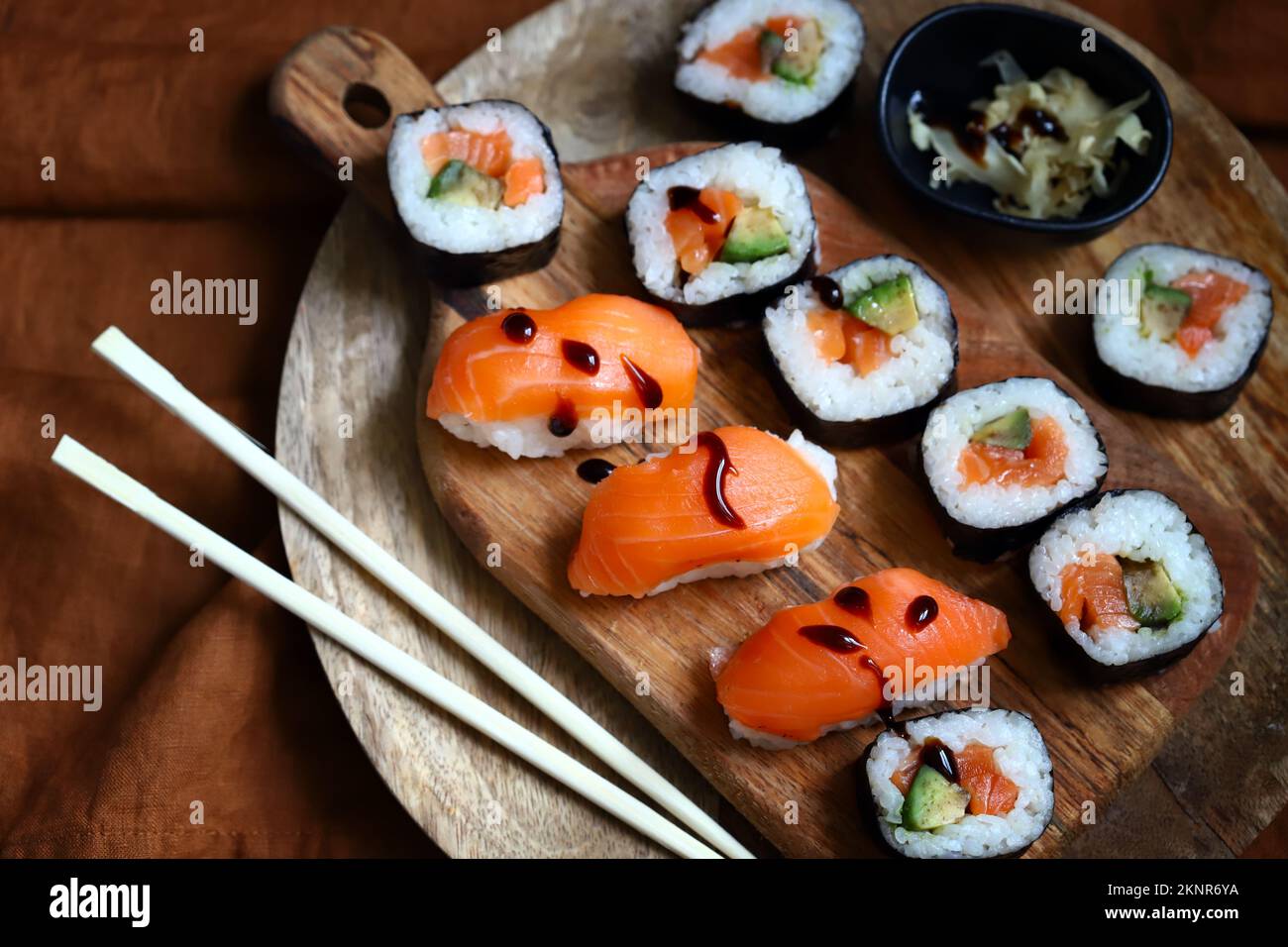 Sushi and rolls with avocado and salmon on a wooden board. Stock Photo