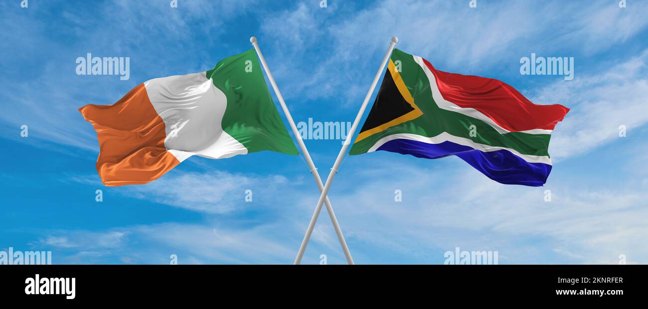 two crossed flags South Africa and Ireland waving in wind at cloudy sky ...