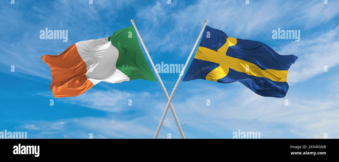 two crossed flags SWEDEN and Ireland waving in wind at cloudy sky ...