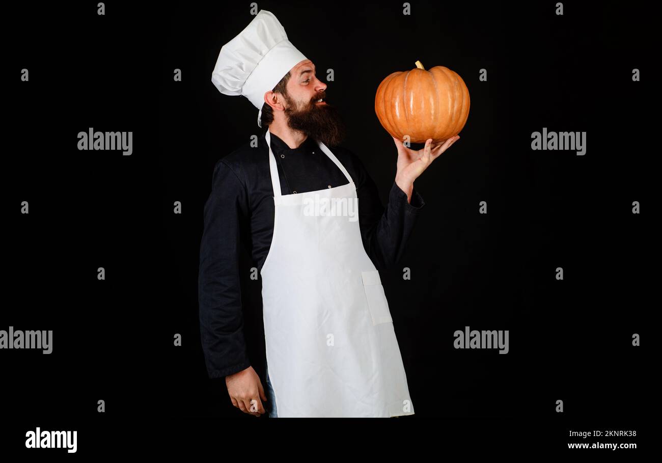 Bearded chef in white apron and hat with pumpkin. Autumn food. Healthy organic harvest vegetables Stock Photo