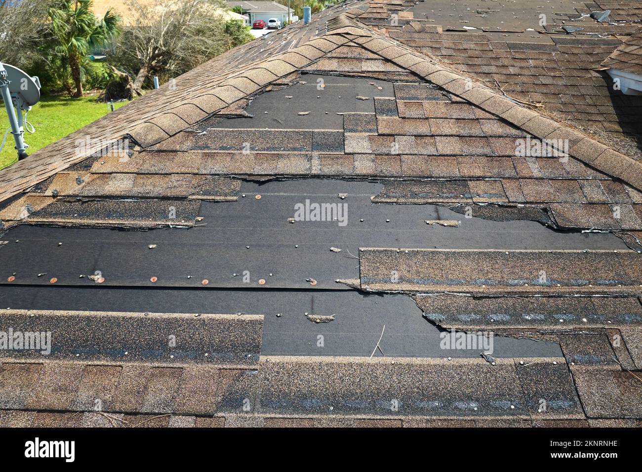 Damaged house roof with missing shingles after hurricane Ian in Florida