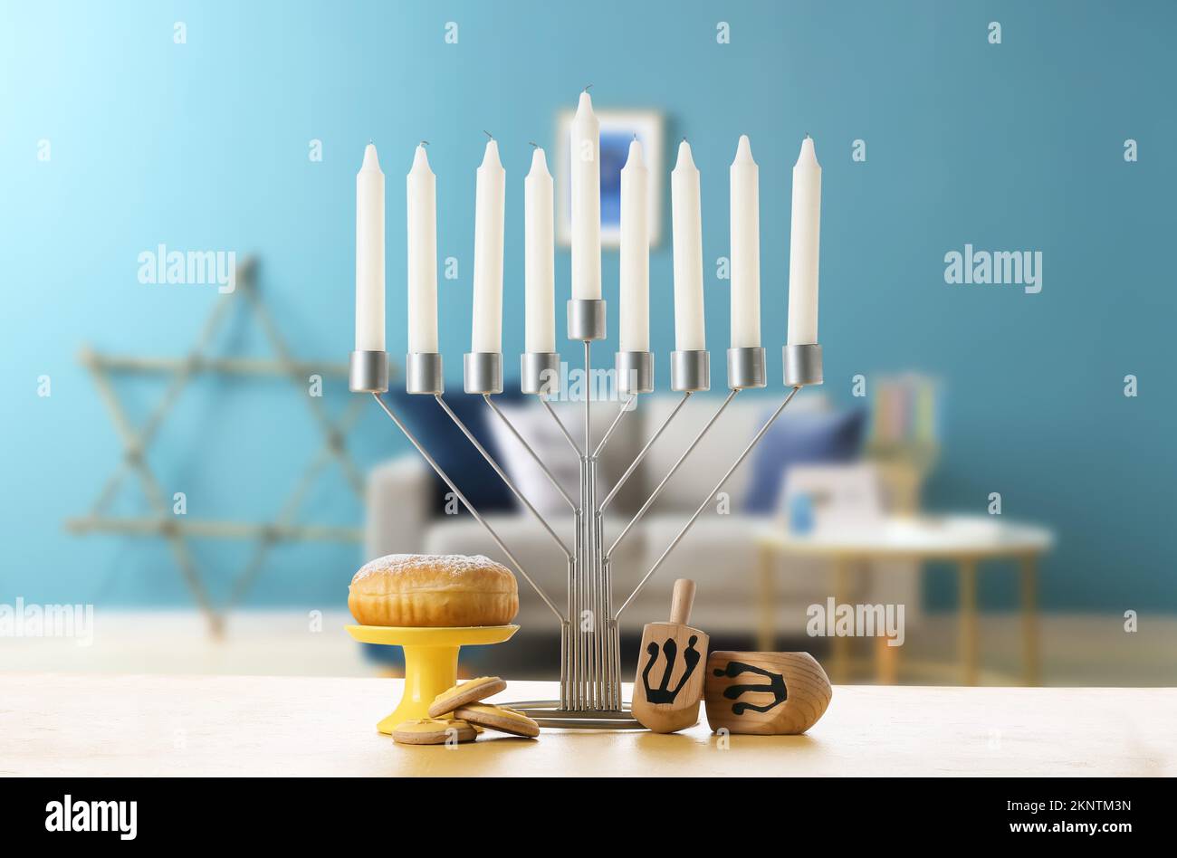 Menorah with dreidels, donut and cookies for Hanukkah on table in room