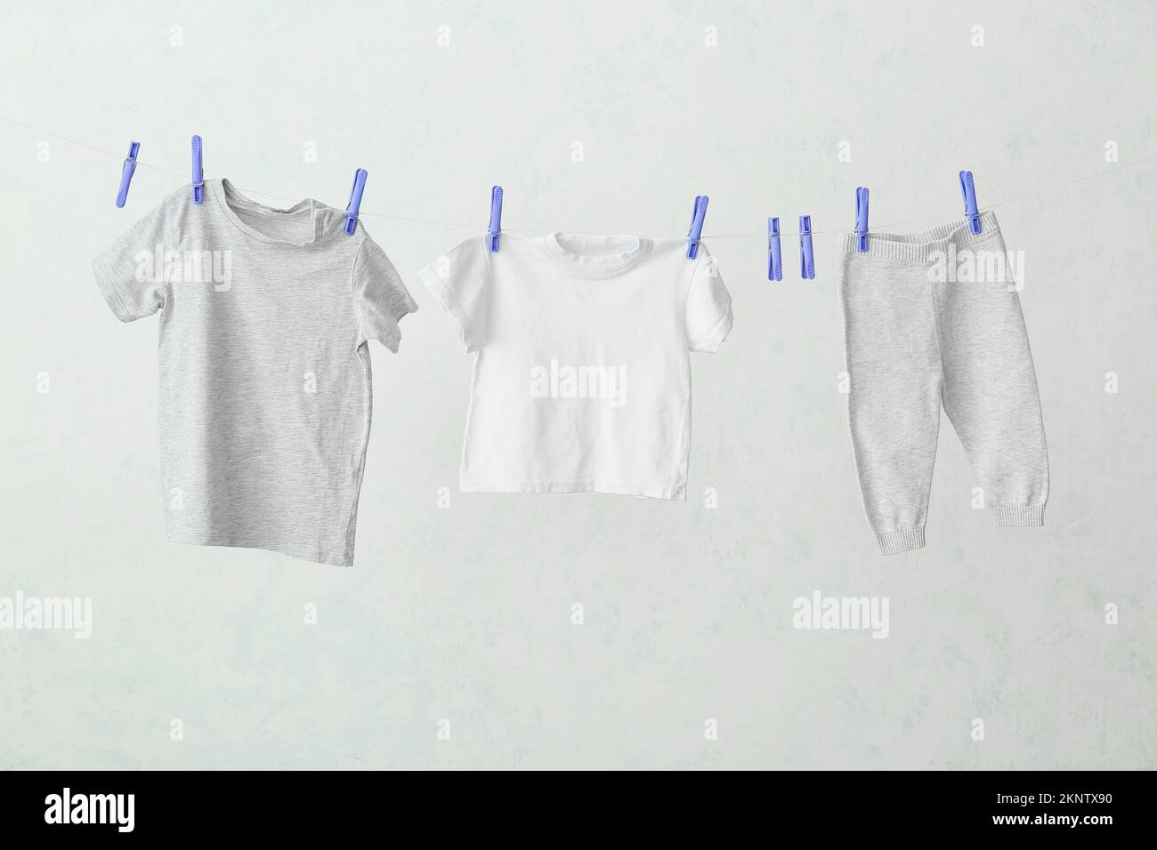 Different baby clothes hanging on rope against light background Stock ...