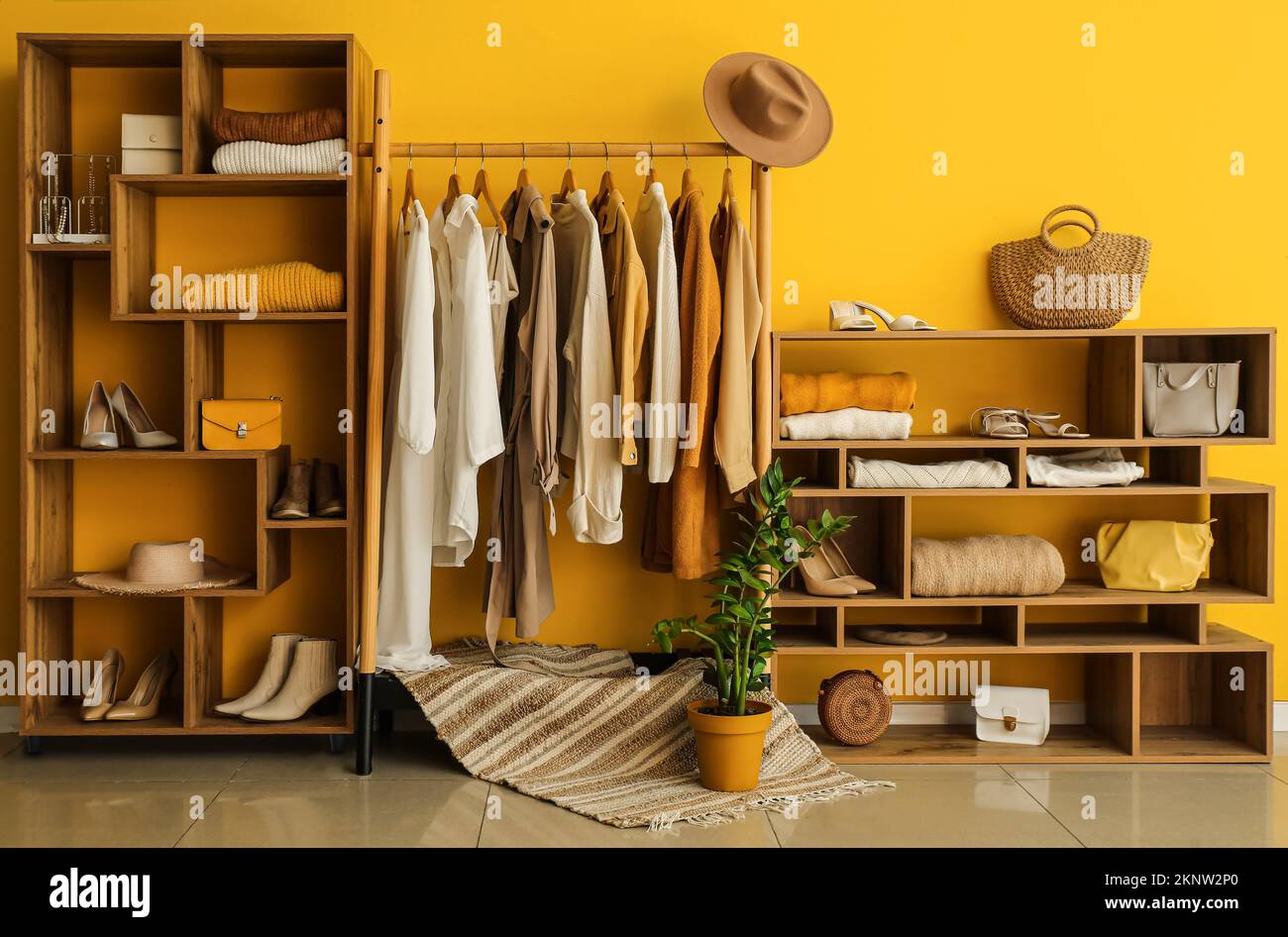 Interior of stylish dressing room with rack, clothes and shelving units