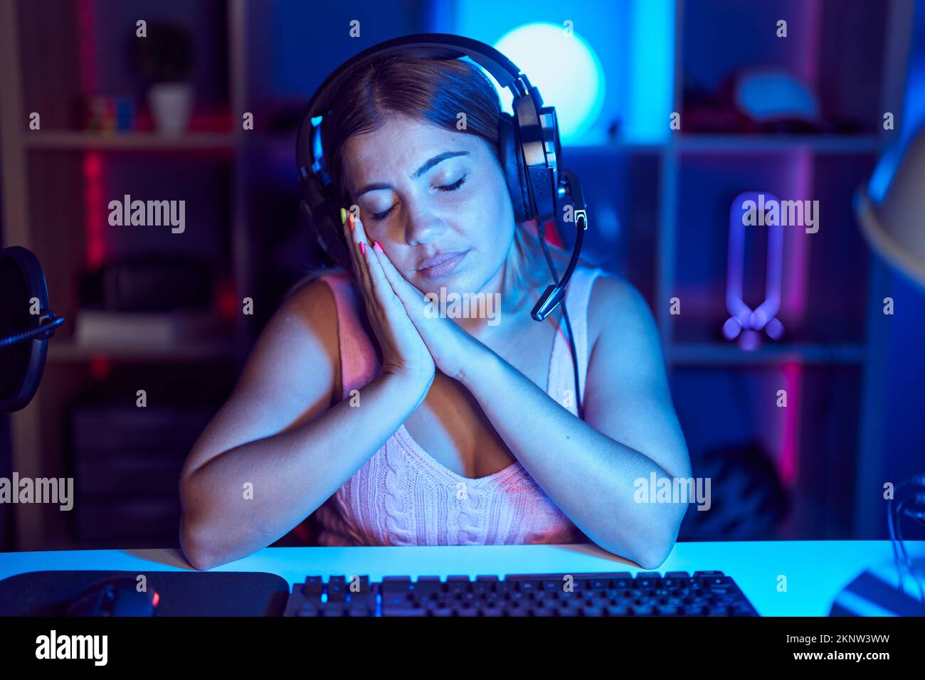 Young blonde woman playing video games wearing headphones sleeping