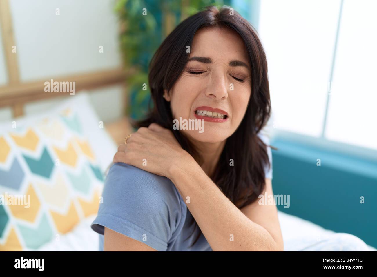 Middle age hispanic woman sitting on bed suffering for shoulder pain at bedroom Stock Photo Alamy