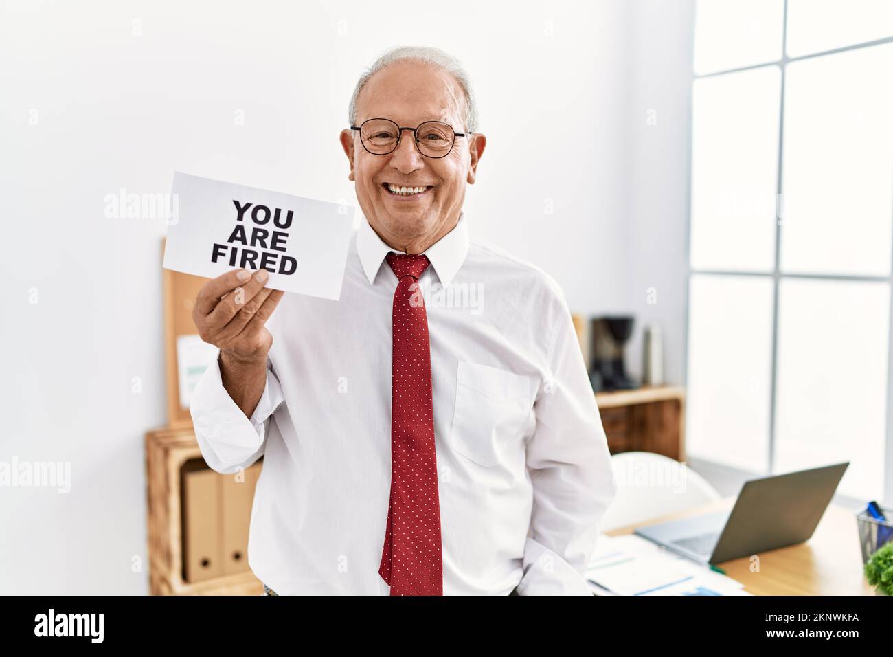 Senior business man holding you are fired banner at the office looking ...