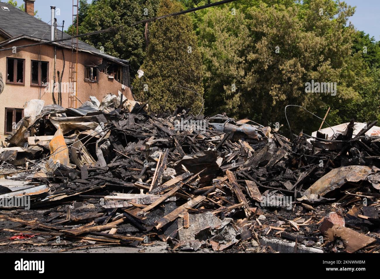 Fire damaged cottage style home next to remnants of burnt down commercial building. Stock Photo