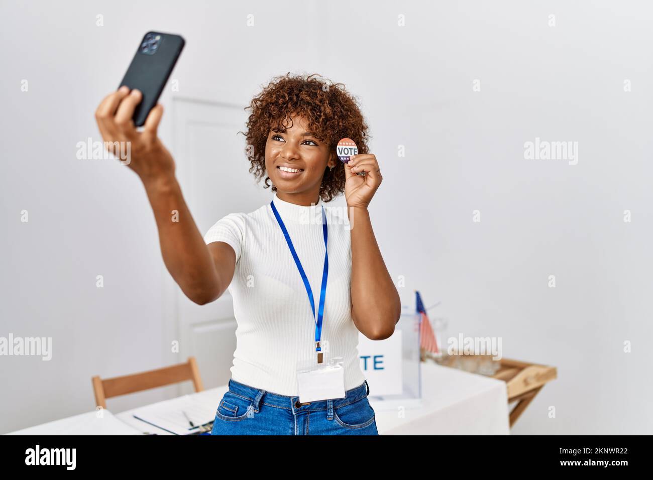 Young african american woman holding badge make selfie by the smartphone at electoral college Stock Photo