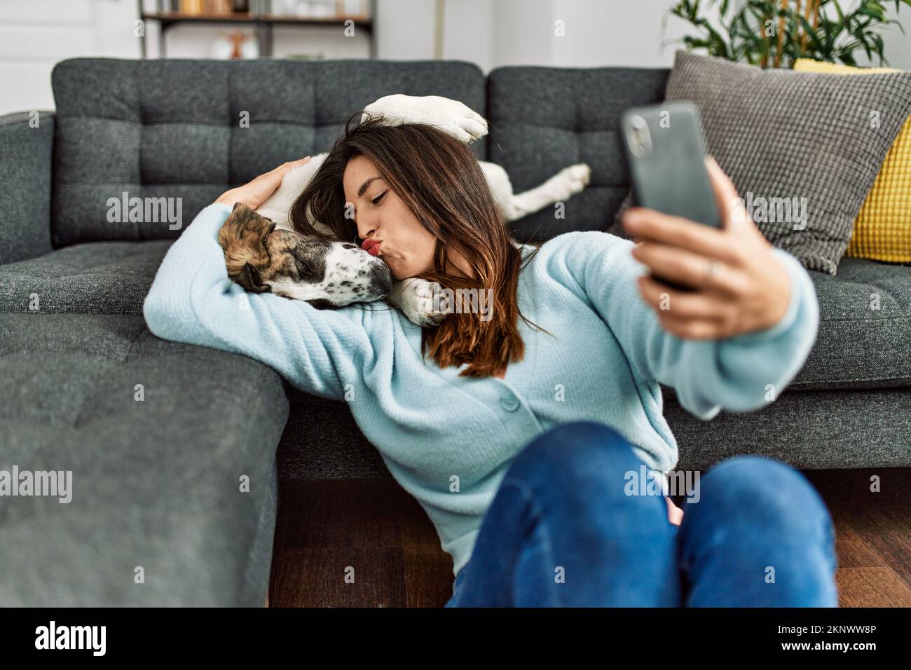 Young woman kissing and hugging dog making selfie by the smartphone at ...