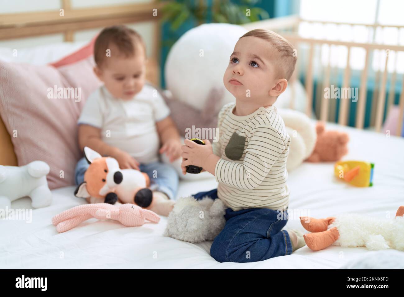 Two adorable toddlers sitting on bed playing at bedroom Stock Photo - Alamy