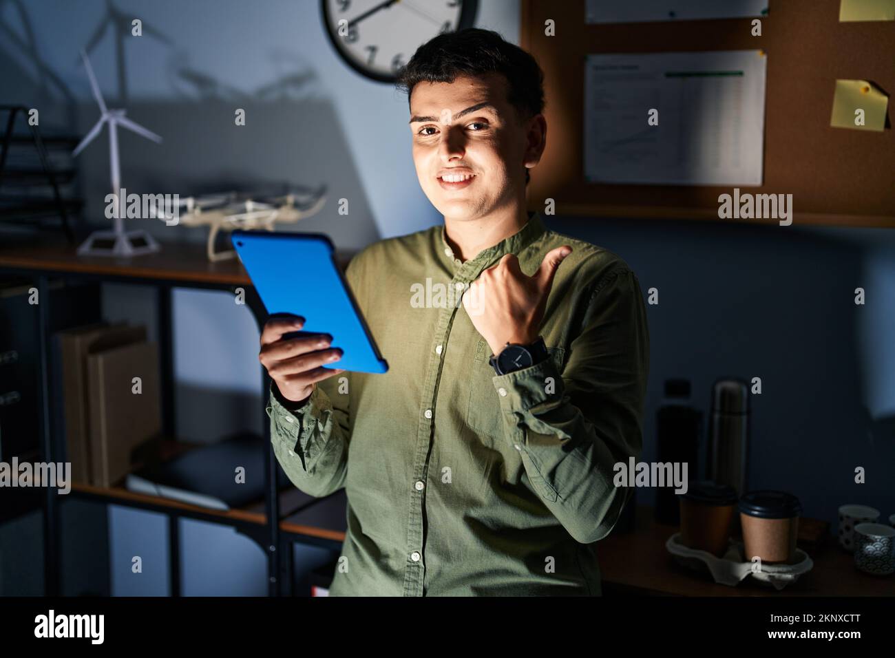 Non binary person using touchpad device at night pointing to the back ...