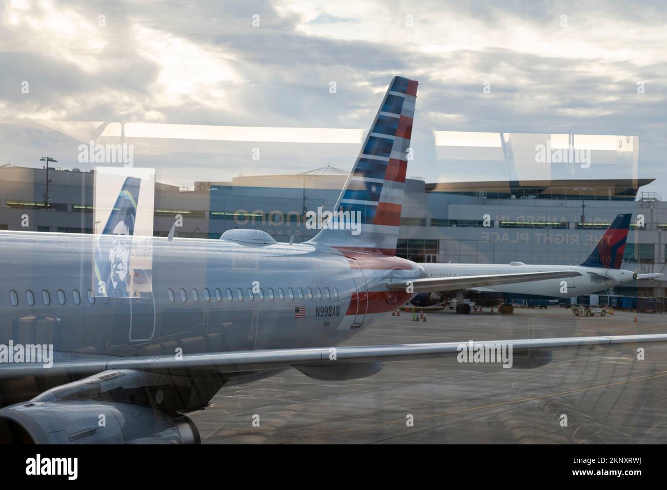 Abstract reflections include the tail of an Alaska Airlines aircraft as