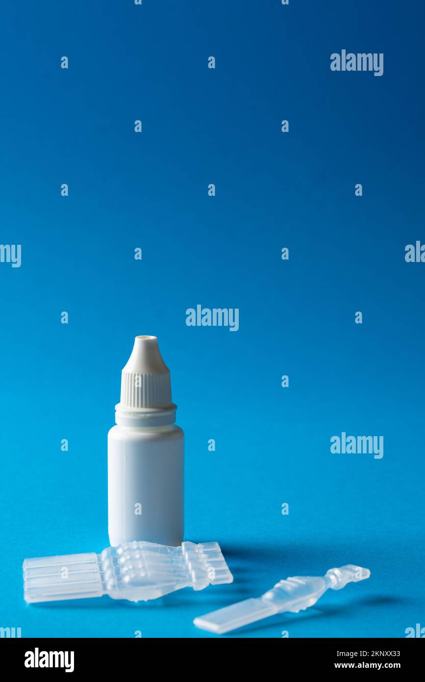 Vertical of saline solution caplets and dropper bottle on blue background with copy space Stock Photo