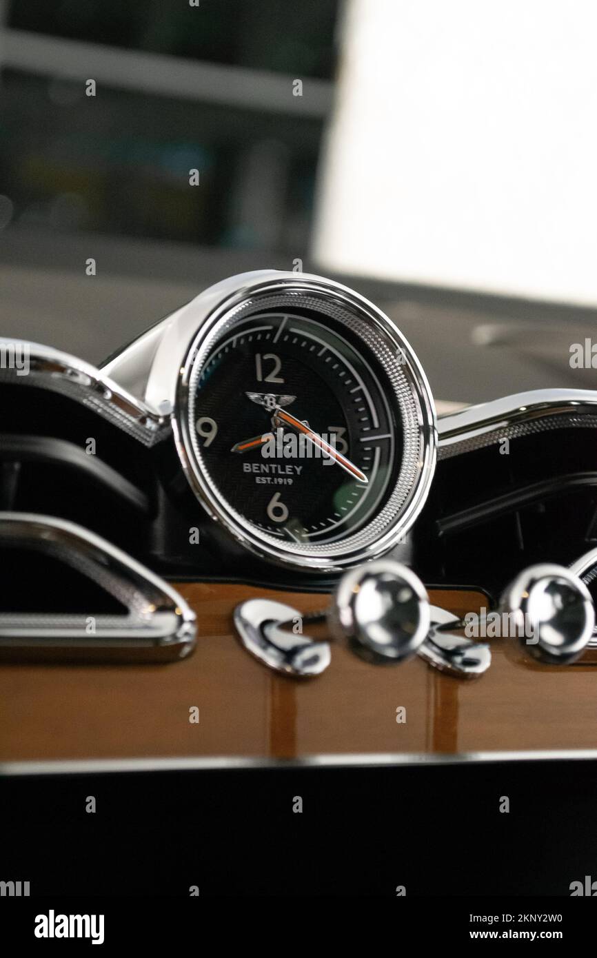 A vertical shot of a Bentley Bentayga dashboard analog clock with a chrome and wood finish Stock Photo Alamy