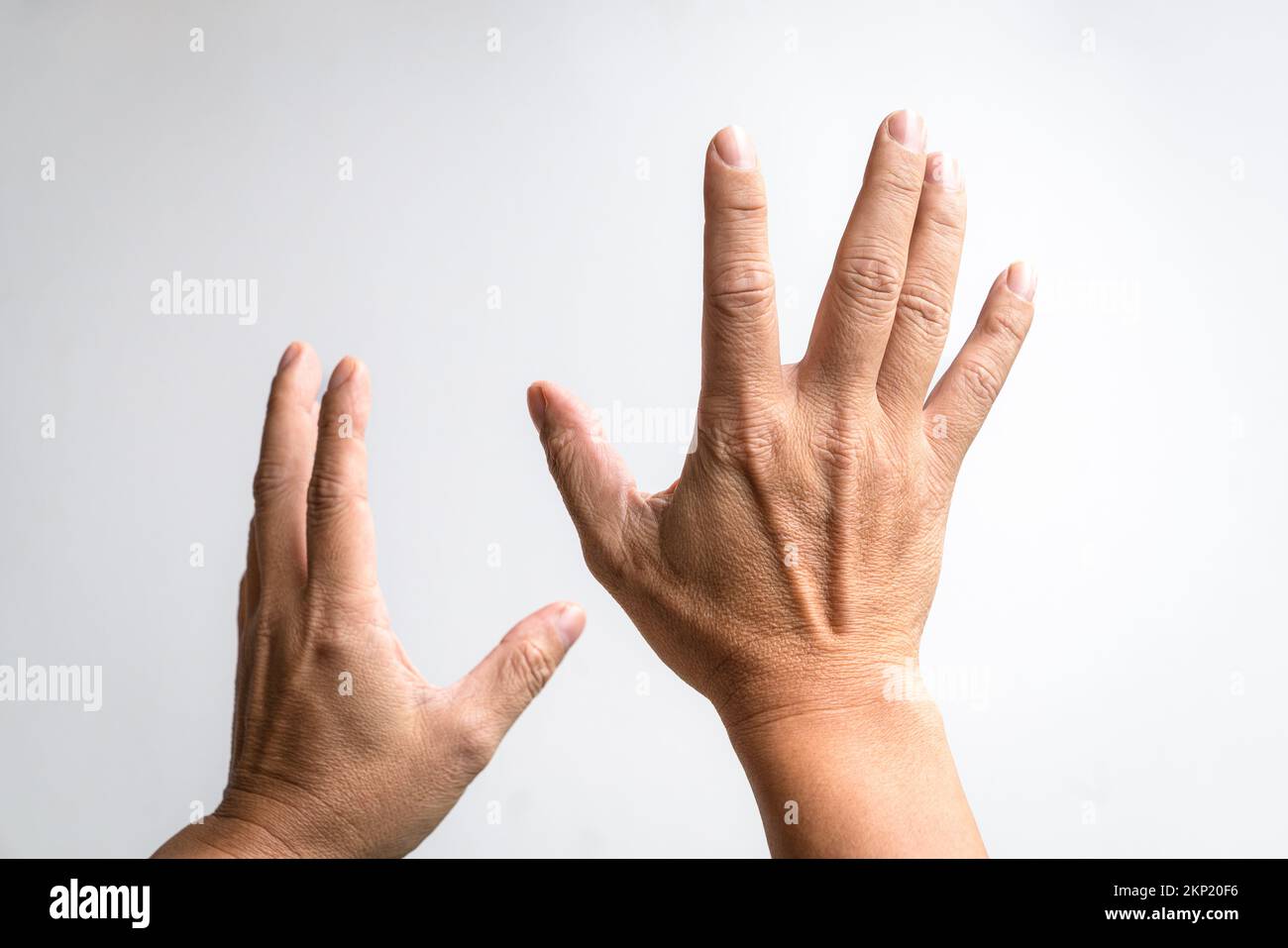 Pair of hands reaching up against white background. Stock Photo
