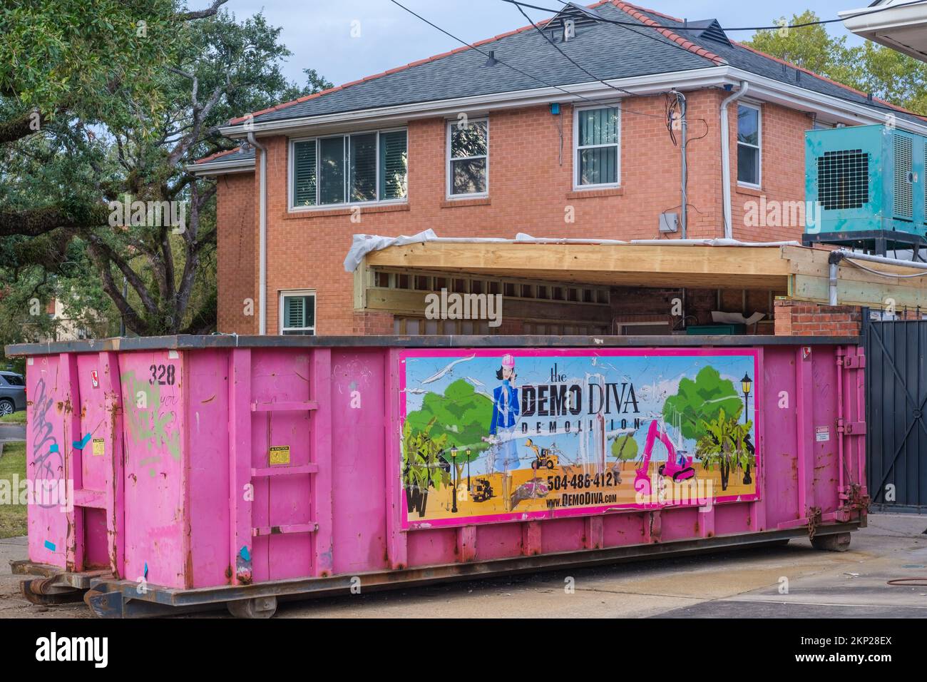 NEW ORLEANS, LA, USA - NOVEMBER 21, 2022: Demo Diva dumpster parked in driveway in front of a garage that is being renovated in an uptown home Stock Photo