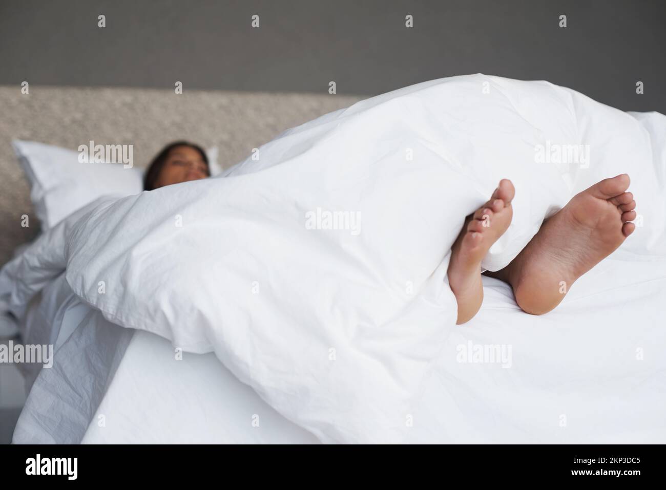 Do you feel a breeze. a young womans feet sticking out of the duvet as