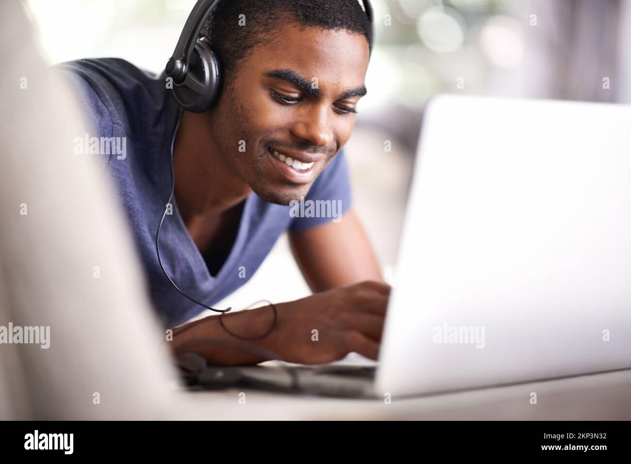 Relaxing while getting his studies done. a handsome young man using his laptop while relaxing at home. Stock Photo