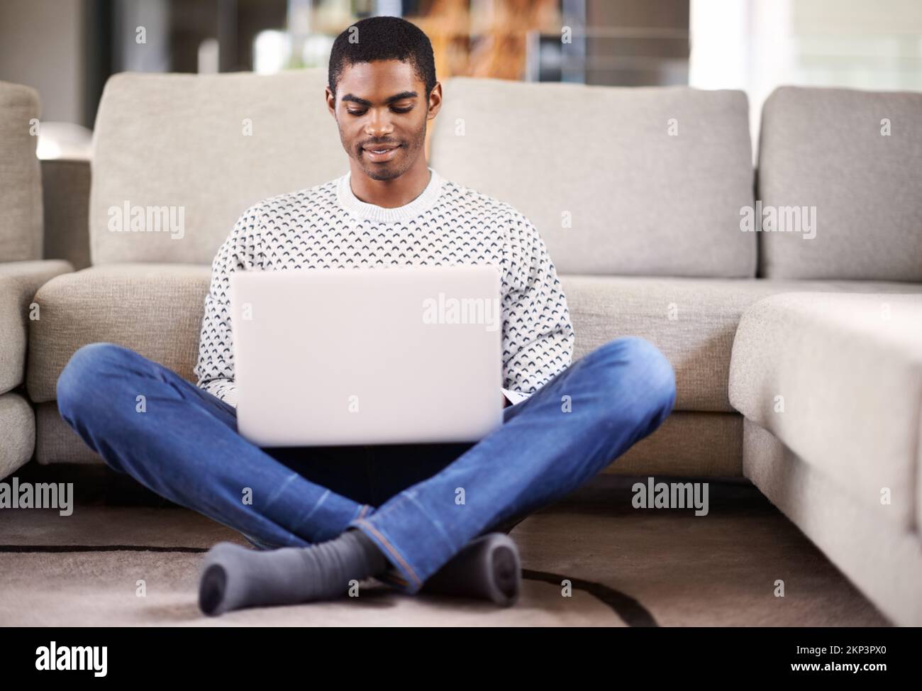 Reaching out to the world. a handsome young man using his laptop while relaxing at home. Stock Photo