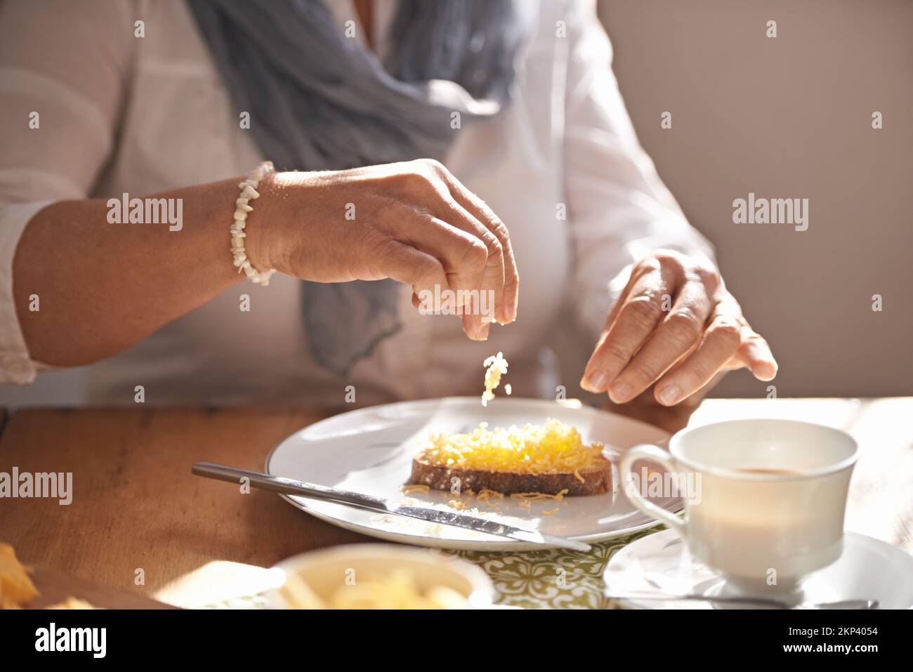 Tea and a light lunch...delicious. Cropped view of a womans hands putting cheese on some bread for lunch. Stock Photo