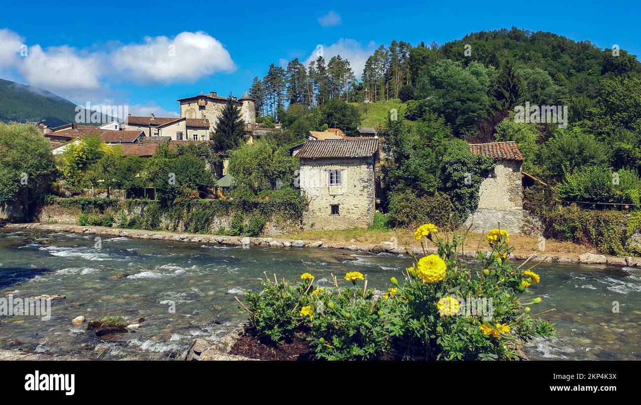 A view of stone houses near the river on the background of a dense forest in Ariege, Occitania, France Stock Photo