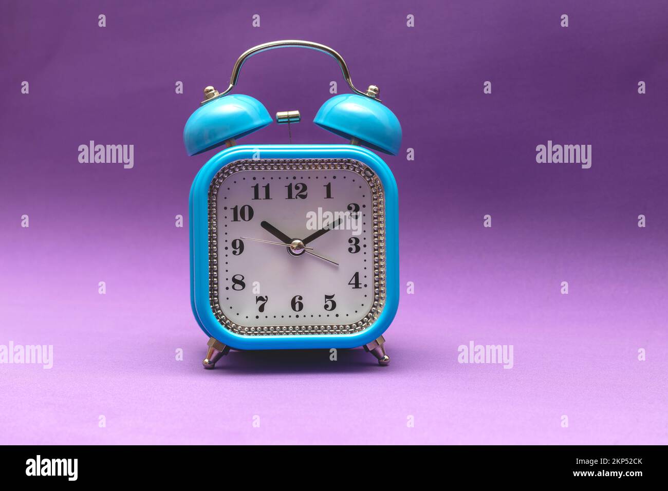 Blue alarm clock on a purple background, soft focus, selective focus