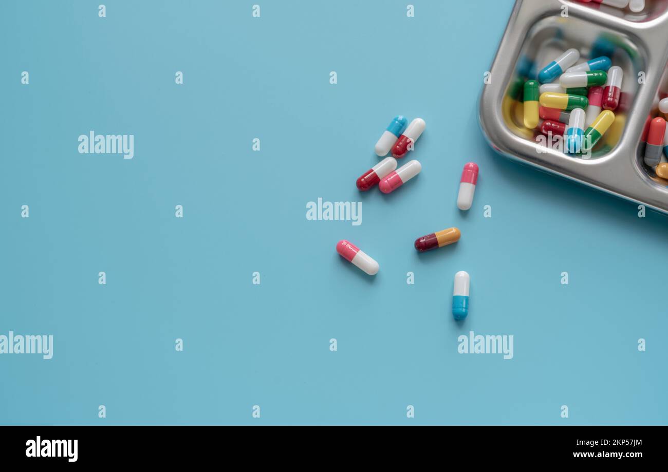 Above view of Colorful antibiotic capsule pills on a tray and blue background. Antibiotic drug