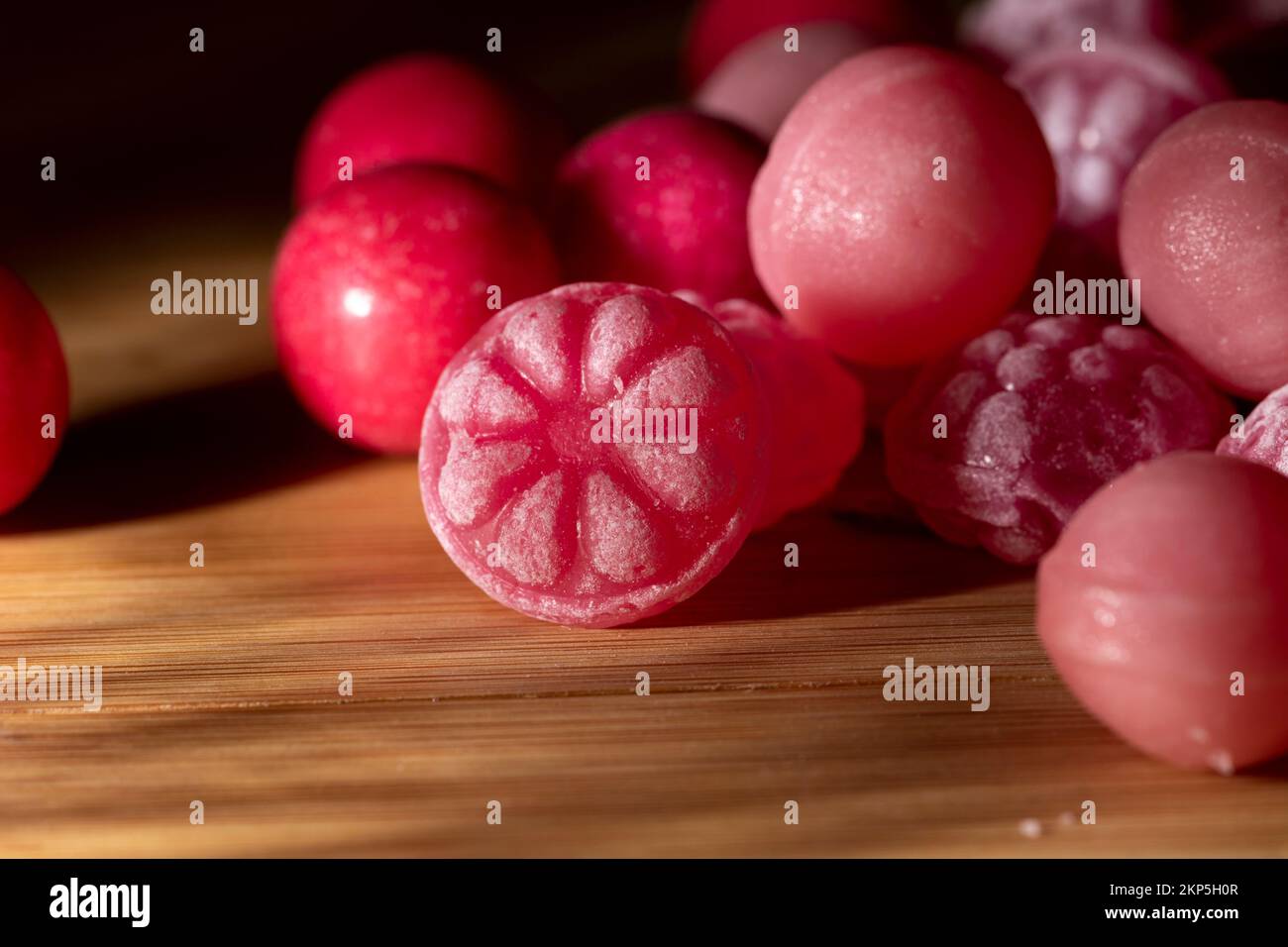 The macro shot of pink raspberry-flavored candies over the wooden surface Stock Photo