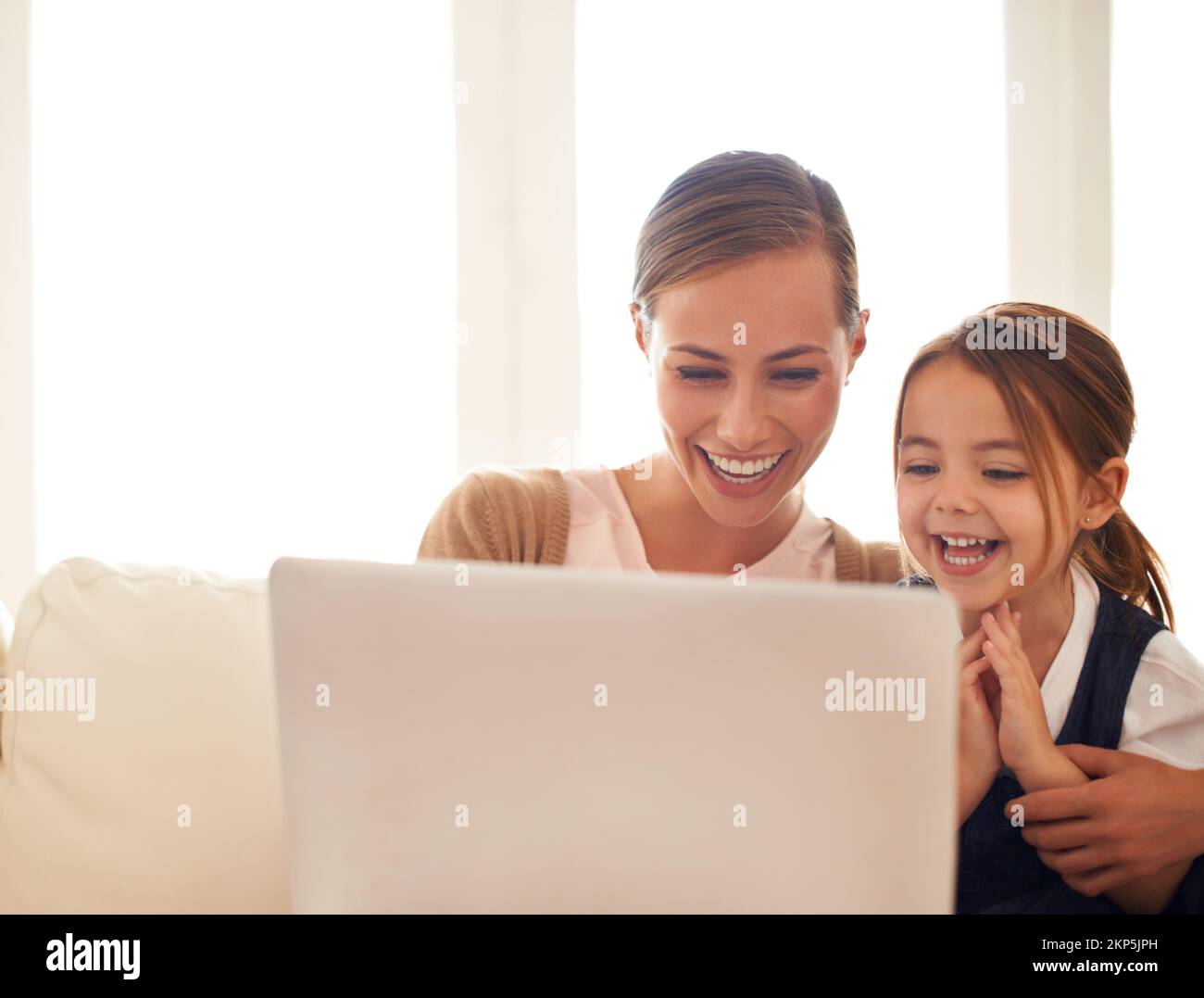 Showing her how to surf. a mother using a laptop with her little ...