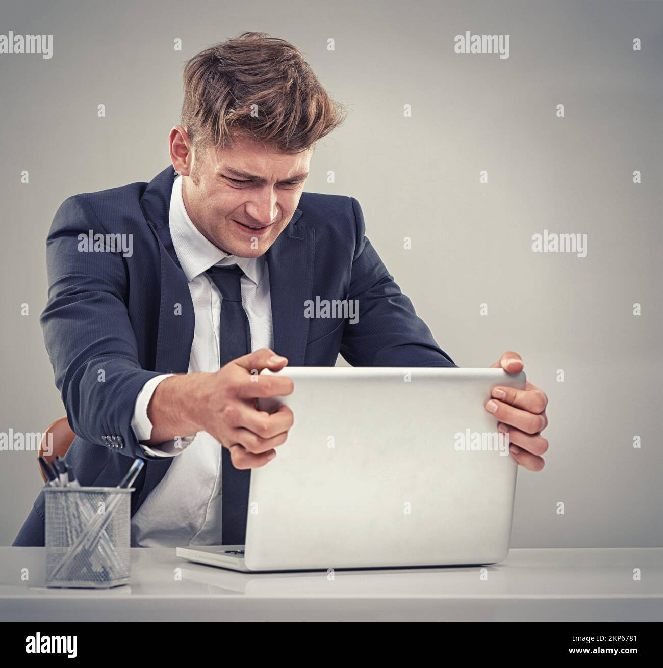 Feeling the strains of a huge corporate job. Young business man looking unhappy at his work desk. Stock Photo
