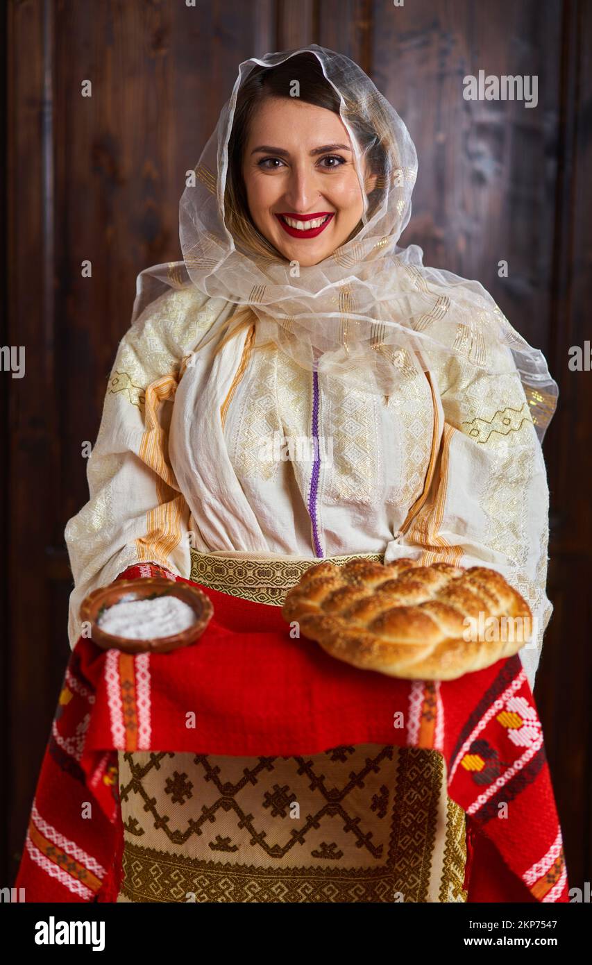 Young Romanian woman in traditional bride popular costume offering bread and salt as welcome Stock Photo