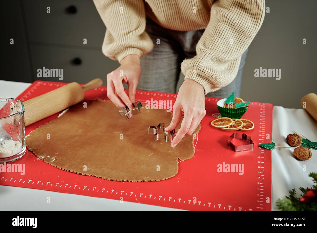 Woman preparing gingerbread cookies at kitchen. Female hands cutting ginger dough with cutter to making cookies for winter holidays Stock Photo