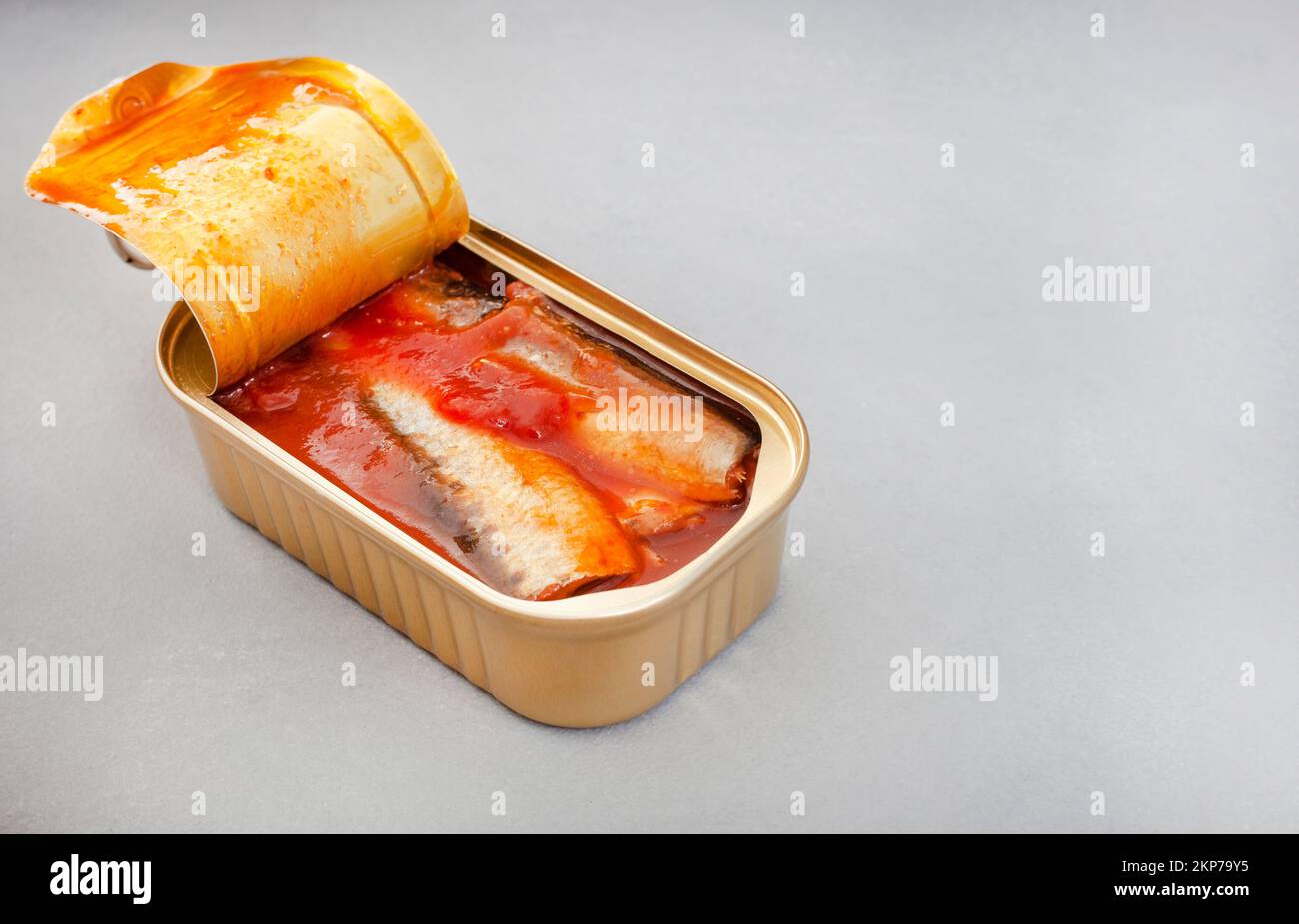 Canned sardines with tomato on grey surface with copy space Stock Photo
