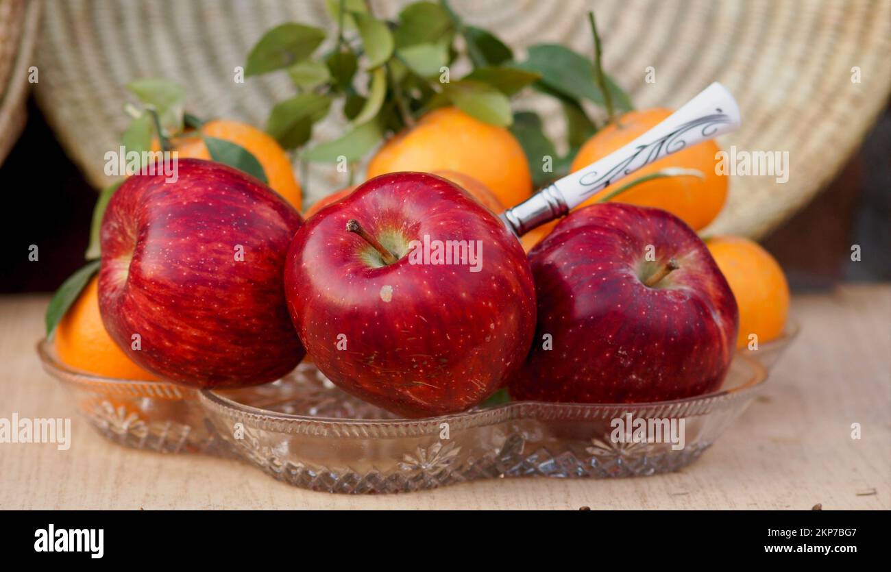 A closeup of red juicy apples and oranges on a glass plate Stock Photo