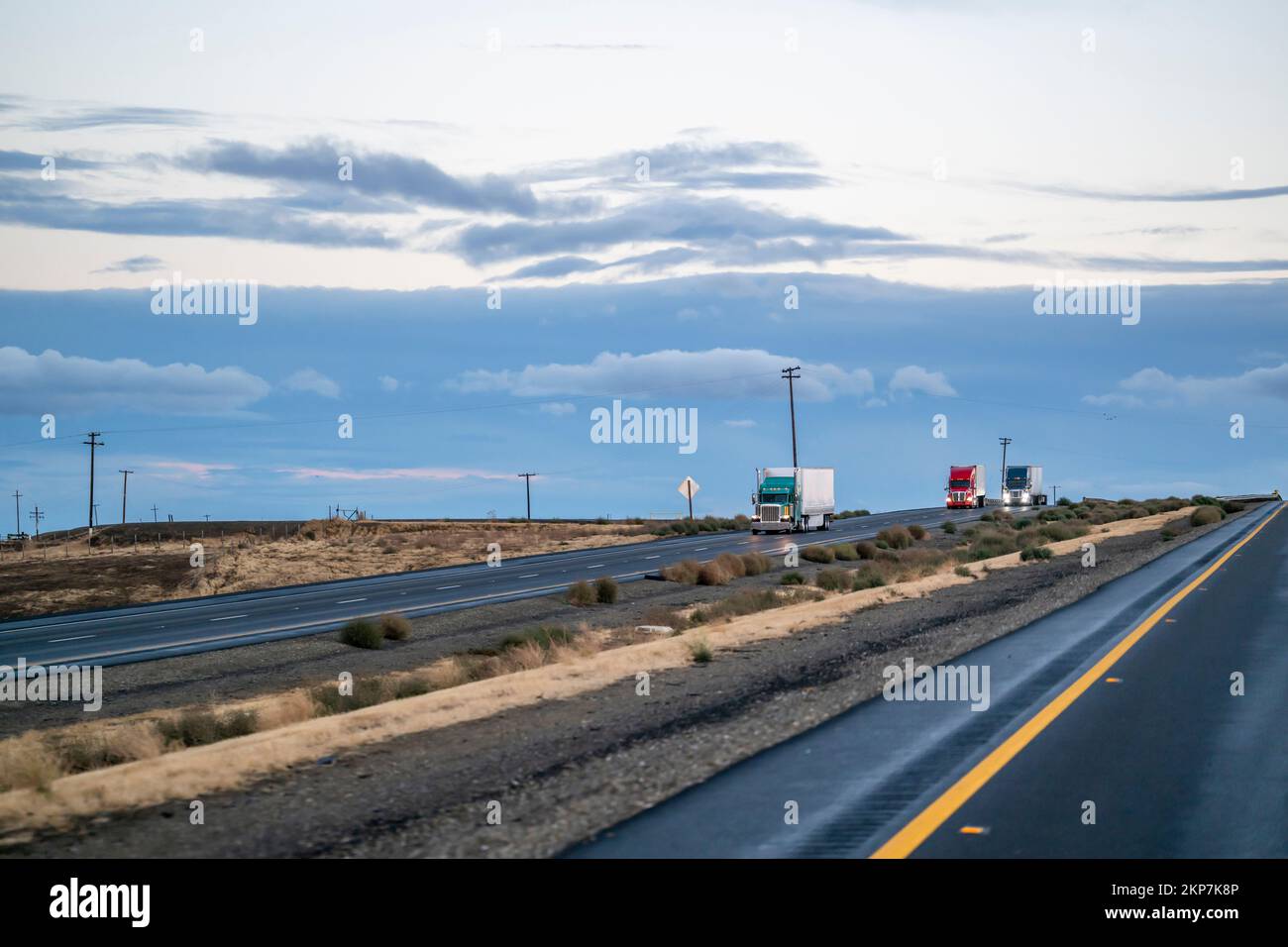 Convoy of industrial big rigs semi trucks with turned on headlights and ...
