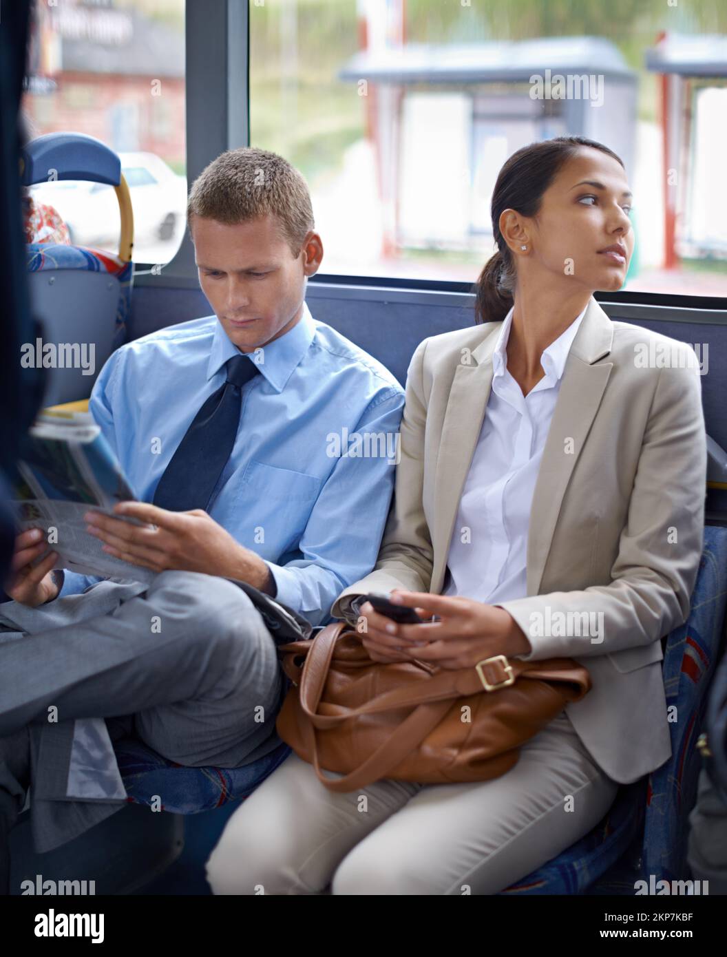 On the way to work. Two young colleagues traveling on the bus together. Stock Photo