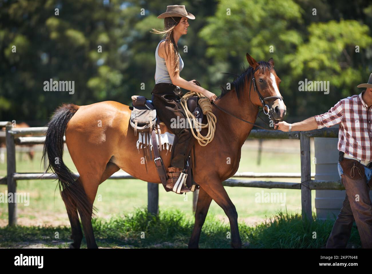 Shes in good hands. a young woman on a horse being led by a farmhand