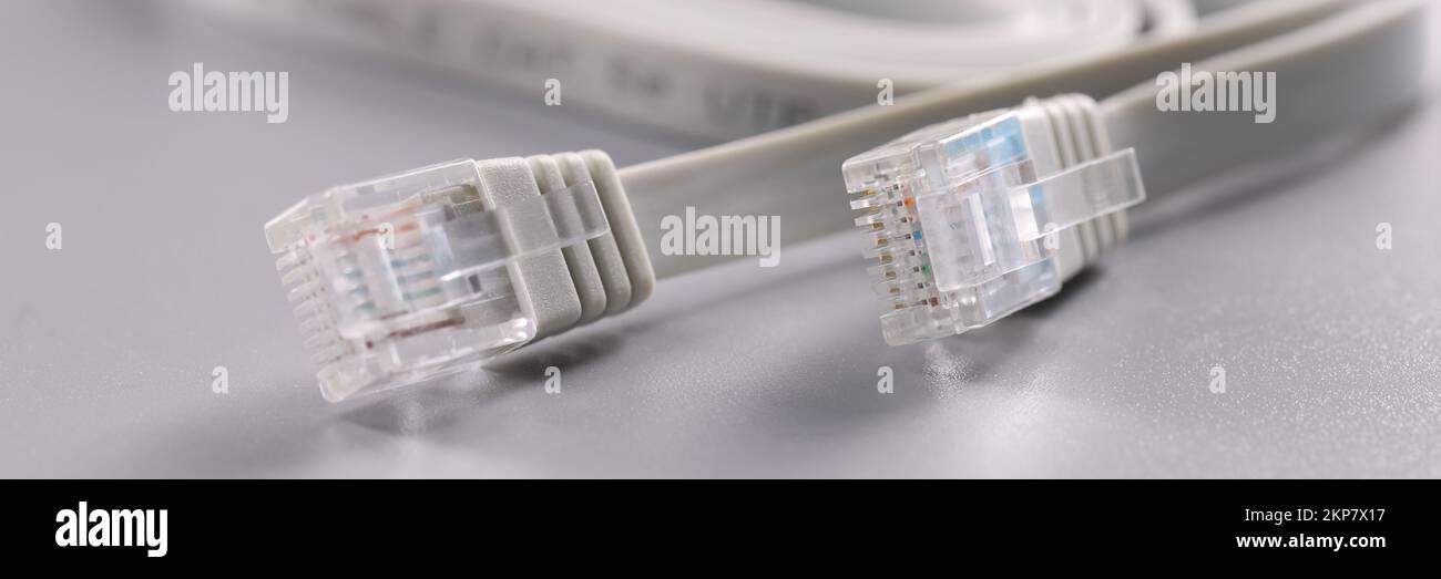 White internet connectors placed on grey surface, cable with plastic clip at tip Stock Photo