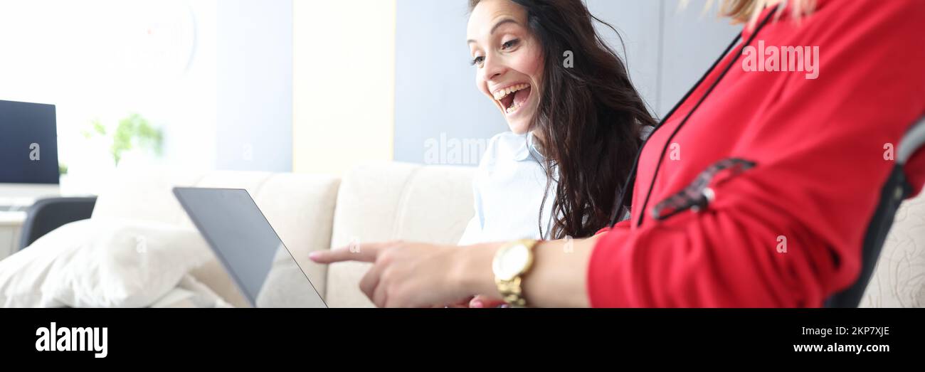 Friends spend time at home, watching movie and laughing, woman in wheelchair with laptop on lap Stock Photo