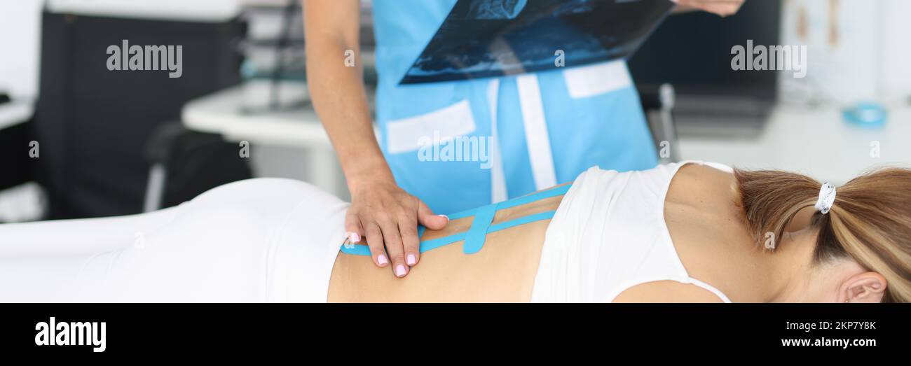 Doctor examine x ray scan, woman with back damage, massaging hurting spots Stock Photo