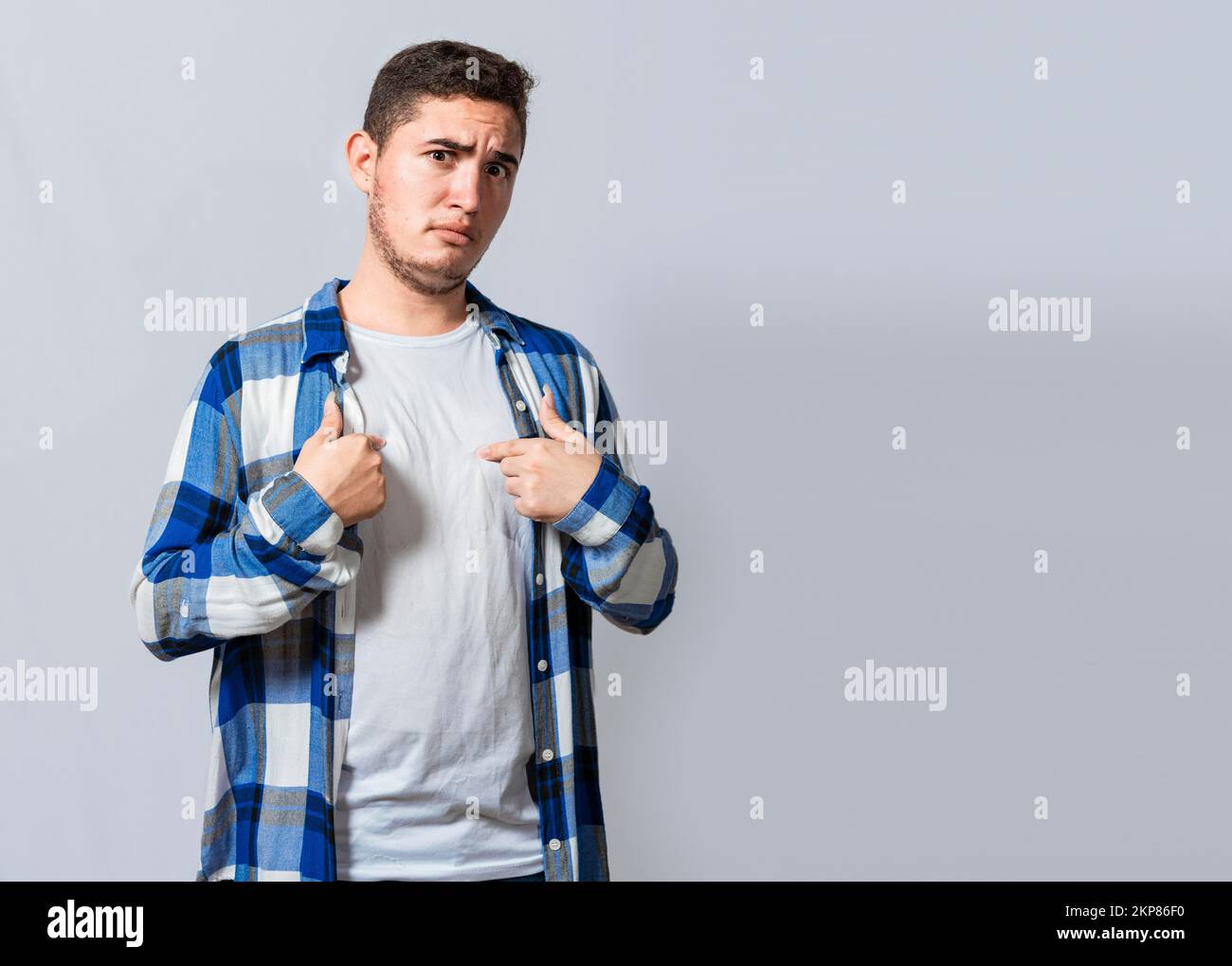 Confused caucasian young man pointing at himself. Confused person pointing at himself isolated. Confused latin guy pointing at himself isolated, Portr Stock Photo