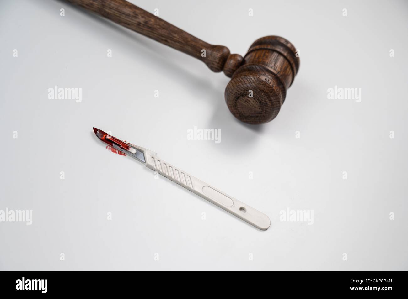 A scalpel covered in blood and a judge's wooden gavel Stock Photo - Alamy