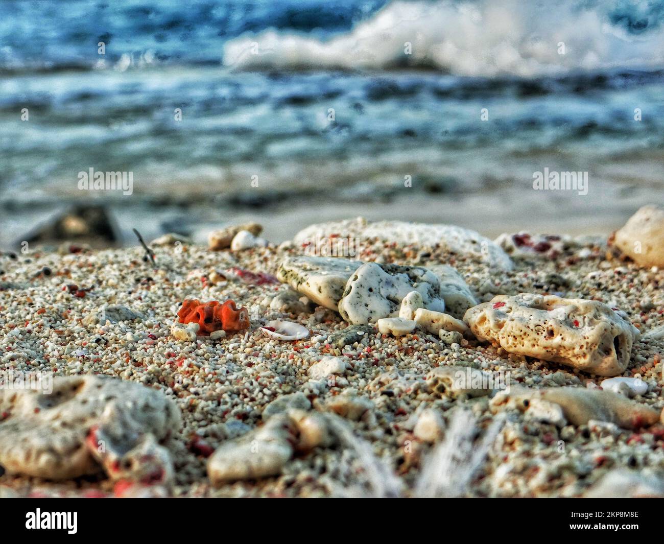 A closeup of rocks and sand in beach in background of sea waves Stock Photo