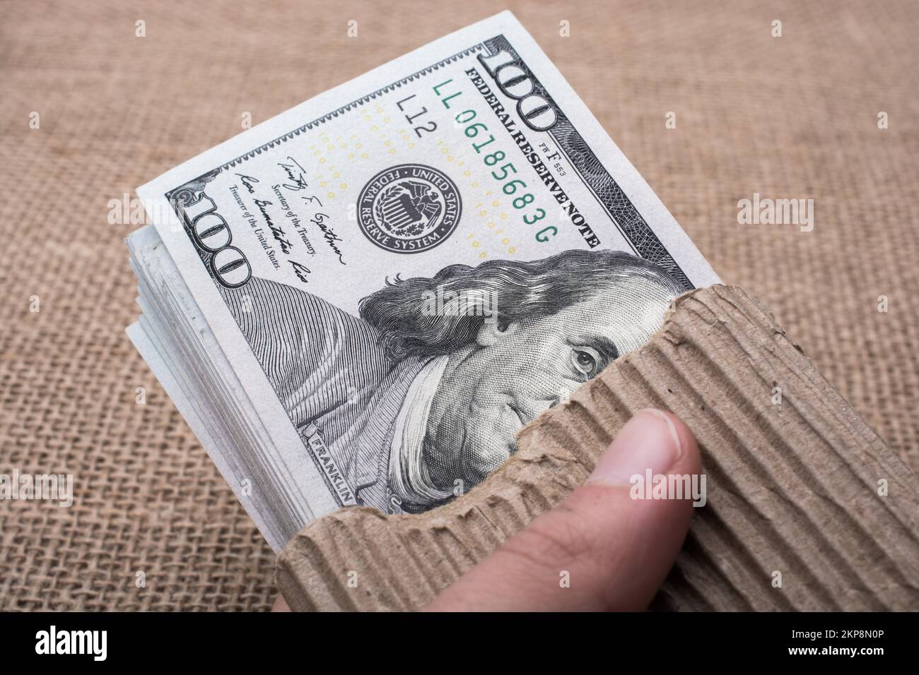 Hand holding banknote bundle of US dollar on a linen canvas background ...