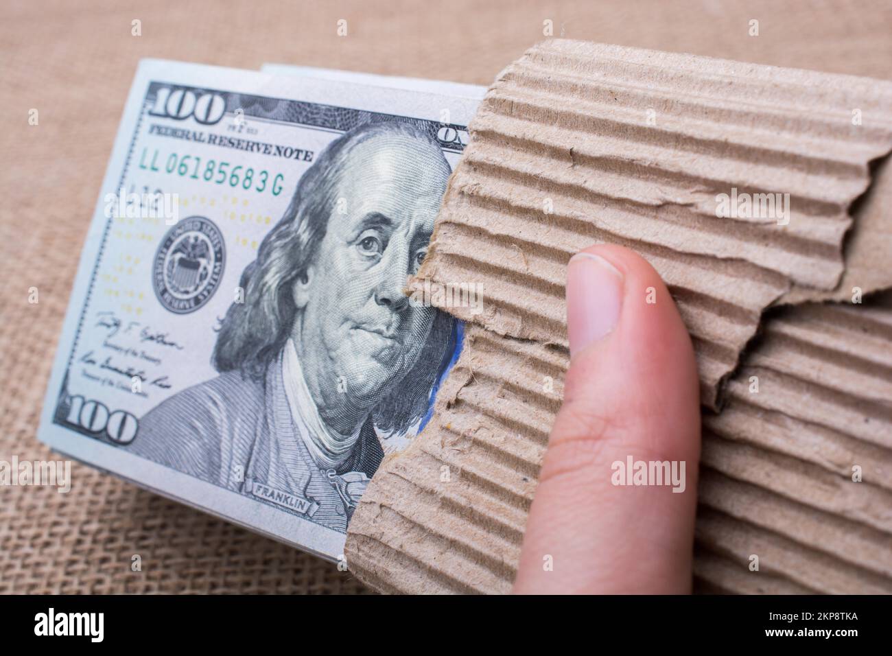 Hand holding banknote bundle of US dollar on a linen canvas background ...