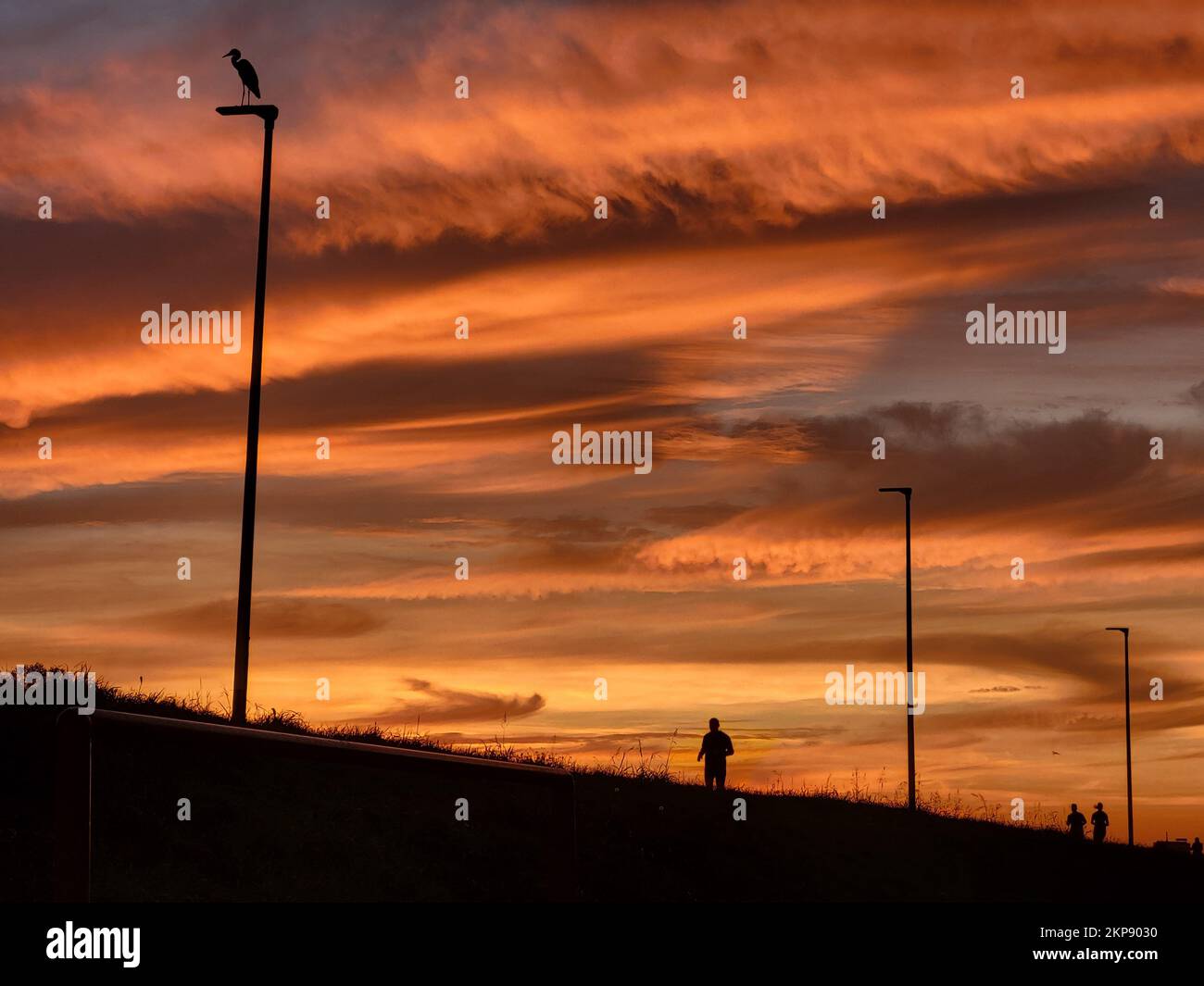 A silhouette of a person under a sunset sky Stock Photo