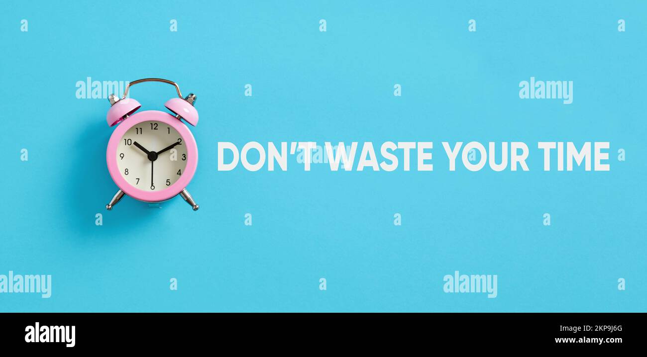 Pink alarm clock on blue background with the message do not waste your