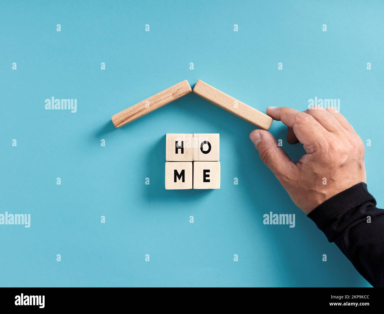 Housing, sheltering, home safety and security concept. Male hand building a house with wooden